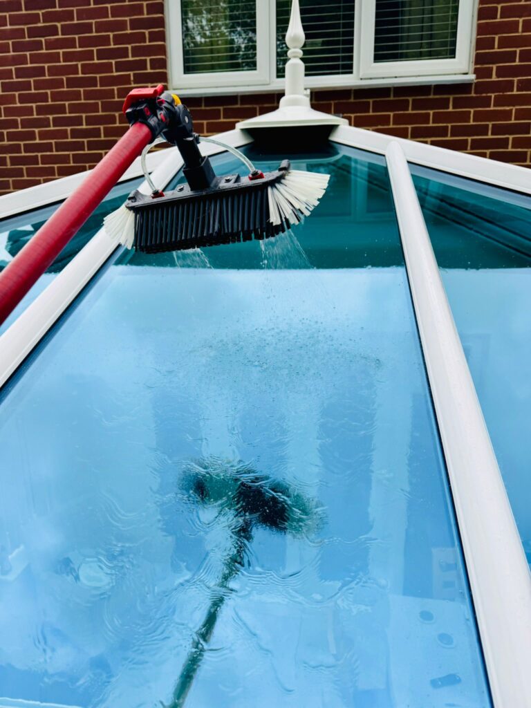 Soft brush rinsing conservatory roof panels during exterior clean in Colchester Essex